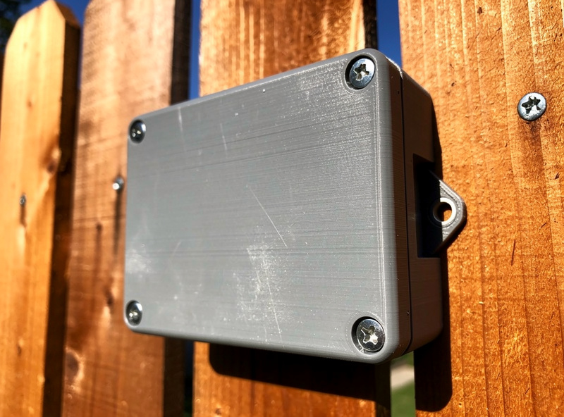 Outdoor mounted ASA 3D printed enclosure box on a wooden fence in direct sunlight showing weather resistance after months of exposure