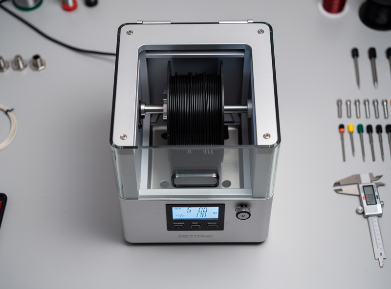Sunlu S2 filament dryer on a workbench with a spool of filament inside the heated chamber and the digital temperature display visible
