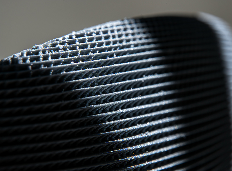 Macro close-up of 0.1mm layer height 3D print showing fine layer lines on a curved sculpture surface