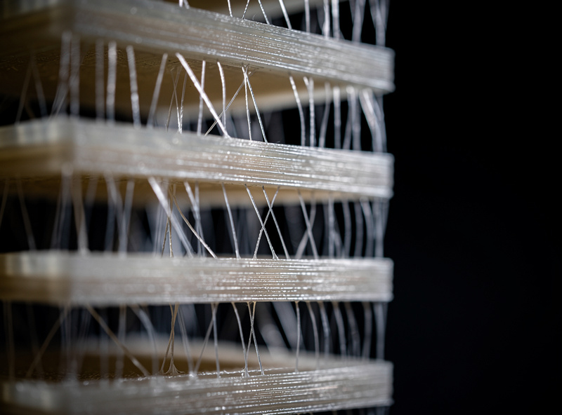 Close-up of a 3D printed PETG temperature tower with visible thin plastic strings between the separated tower segments at different print temperatures