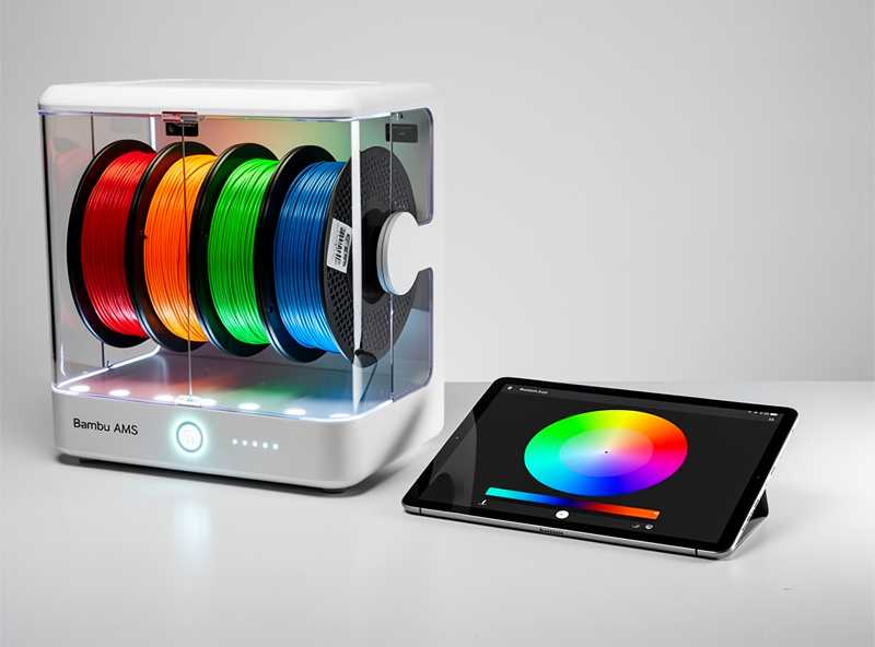 Bambu AMS unit with four filament spools loaded and color picker showing rainbow palette