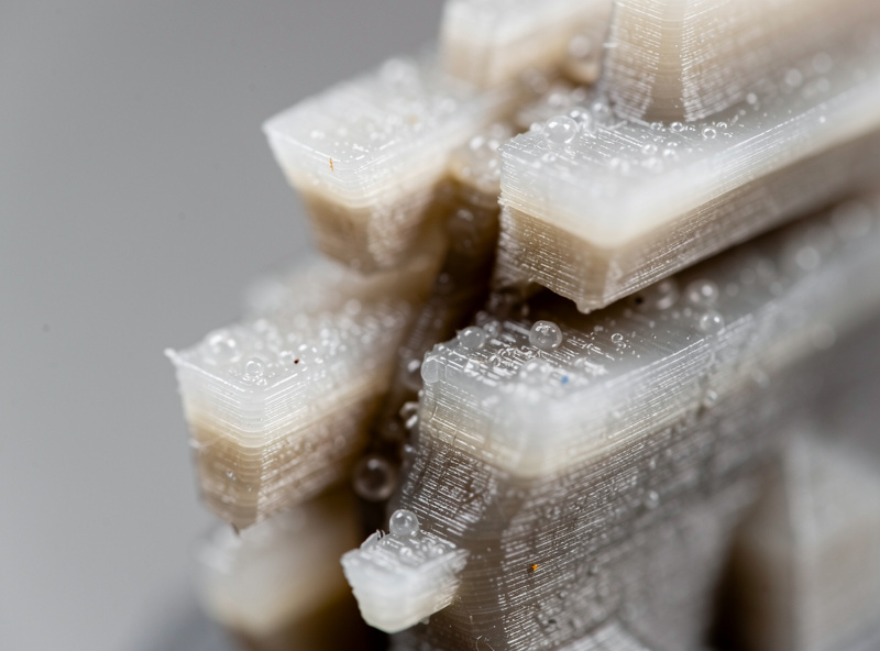 Close-up of a resin print showing delaminated split layers partway up the model