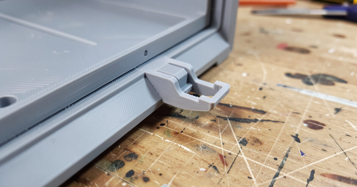 A 3D printed cantilever snap-fit clip engaging with a ledge